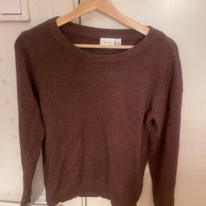 Brun stickad tröja från Vila - Säljer en mysig brun stickad tröja från Vila. Tröjan har en rund halsringning. pPerfekt för kyligare dagar. Den är enkel och stilren, vilket gör den lätt att matcha med olika outfits. Använd runt 3 gånger 