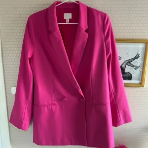 Rosa kavaj från H&M - Snygg rosa kavaj från H&M i en härlig färg. Kavajen är oversized med knappar framtill och långa ärmar. Perfekt för att liva upp garderoben med lite färg!