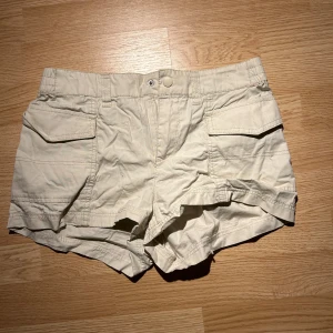 Beige shorts från Divided - Säljer ett par låg midjade beige shorts från Divided. De har en bekväm elastisk midja och praktiska fickor framtill. 🔥