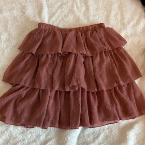 Rosa volangkjol från Vintage Dressing - Charmig rosa kjol med volanger från Vintage Dressing.🎀Kjolen har en elastisk midja för en bekväm passform. Den är kort och har ett prickigt mönster som ger en stilren look. ✨