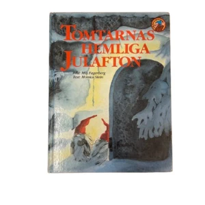 Tomtarnas hemliga julafton - En charmig bok med titeln 'Tomtarnas hemliga julafton' med illustrationer av Møll Fagerberg och text av Monica Stein. Omslaget visar en vintrig scen med tomtar i en snöig skog, vilket ger en mysig julkänsla. Perfekt för högläsning under julen!