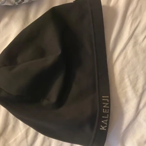 Svart mössa från Kalenji - Säljer en svart mössa från Kalenji, perfekt för löpning eller andra utomhusaktiviteter. Den är tillverkad i ett mjukt och stretchigt material som sitter bekvämt på huvudet. Mössan har en diskret logga och är i mycket bra skick. Perfekt för höst och vinter!