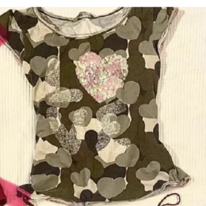 Camouflagefärgad t-shirt med hjärtan - T-shirt med camouflagemönster och korta ärmar.