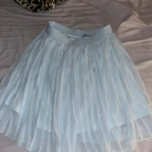 Ljusblå kjol från NA-KD - Säljer en superfin vit kjol från NA-KD. Den har ett härligt voluminöst tyg som ger en snygg look. Perfekt för sommarens alla fester eller bara en dag på stan. Resår i midjan för extra komfort. 🩶