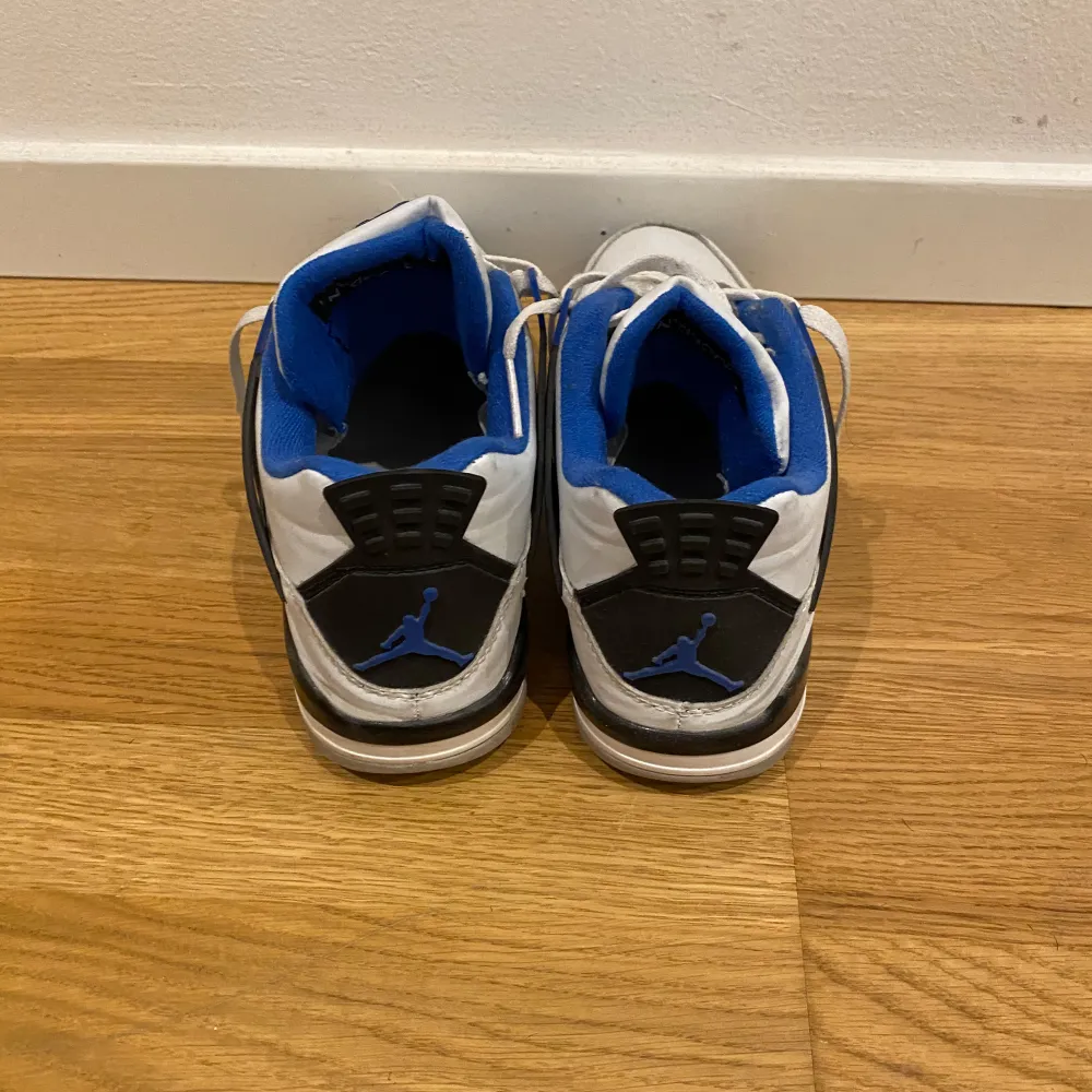 Snygga Nike Air Jordans i vitt med blå och svarta detaljer. Skorna har snörning och en ikonisk design med nätpaneler och Jumpman-logga. Perfekta för sneakerheads som vill ha en klassisk stil.. Skor.