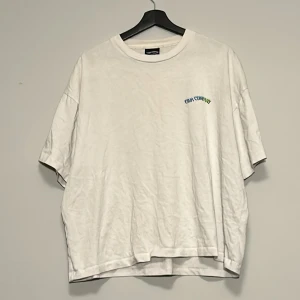 Vit t-shirt med färgglatt blommönster - Vit T-shirt med tryck från The Cava Company. Oversized storlek.