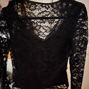 Svart spetsblus - Elegant svart spetsblus med långärmad design och v-ringad hals. Perfekt för fest eller bara till vardags☺️☺️❣️aldrig använd! Storlek Xs