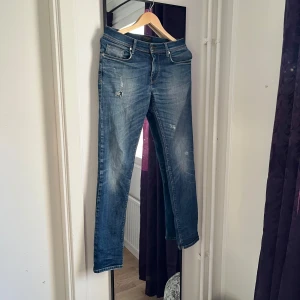 Blå jeans från J.Lindeberg - Snygga blå jeans från J.Lindeberg med en klassisk femficksdesign och diskreta slitningar för en trendig look. Perfekta för en avslappnad stil. Skicket är bra men dem har ett litet litet hål i skrevet! Skriv till mig om du undrar något💯🤷‍♂️💭😃