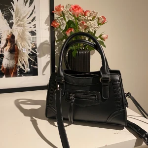 Svart handväska med dragkedja - Snygg svart handväska i skinn med praktisk dragkedja framtill. Väskan har dubbla handtag och en avtagbar axelrem för flexibilitet 💕💕