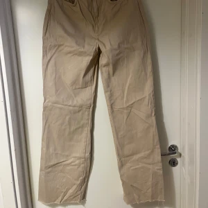 Beige byxor från Stradivarius - Säljer ett par beige byxor från Stradivarius i long straight fit. Byxorna har en hög midja och raka ben i storlek 40. 