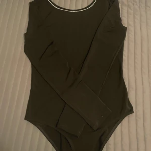 Svart body från H&M - Snygg svart body från H&M med långa ärmar och en glittrig kant runt halsringningen 🖤