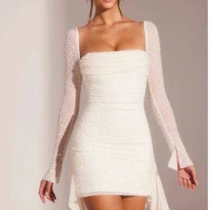 Vit pärlbeströdd klänning - Elegant vit klänning med pärlbroderi och långärmad design. Den har en tight passform och en kort längd, perfekt för speciella tillfällen. Klänningen har en fyrkantig urringning och en subtil slits för extra stil. Köpt från OhPolly inför studentfest använd en gång vilket betyder att den är nästan som ny! Priset kan diskuteras! Dock har jag klippt bort och sytt in sidorna som stack ut, vill ytterligare frågor kontakta mig 😊storlek UK4 