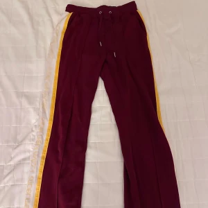 Mjukisbyxor från Calvin Klein - Snygga vinröda mjukisbyxor från Calvin Klein med detaljer längs sidorna. Byxorna har en bekväm passform med dragsko i midjan och sidofickor. 
