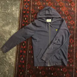 Säljer en snygg mörkblå hoodie från Lyle & Scott med dragkedja och huva. 