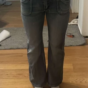 Blå bootcut jeans - Snygga blå bootcut jeans med låg midja och dubbla knappar fram. Jeansen har en klassisk femficksdesign och en lätt tvättad look. Perfekta för en avslappnad stil.