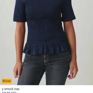 Mörkblå smocktopp - Snygg mörkblå smocktopp med korta ärmar och volangdetalj vid nederkanten. Perfekt för en stilren look.