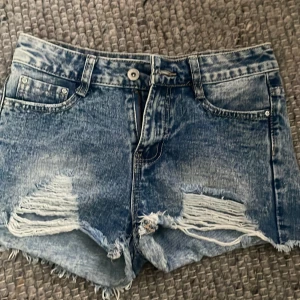 Blå jeansshorts med slitningar - Blåa lågmidjade shorts med slitningar, perfekta till sommaren och trendar nu