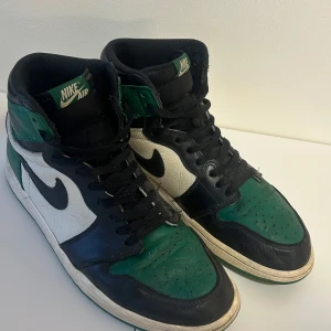 Nike Air Jordan Retro 1’s - Pine Green - Säljer ett par ikoniska Nike Air Jordan 1 Retro High OG 'Pine Green' i storlek 44. Skorna är i gott skick med normala tecken på sparsam användning, därav det förmånliga priset. Går för $300 minst på StockX.  Skorna är mycket populära och är ett bra tillägg till din sneakerkollektion. Dessutom otroligt bekväma för fötterna.