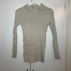 Beige ribbad polotröja - Säljer en stilren beige ribbad polotröja med långa ärmar. Perfekt för kyligare dagar och enkel att matcha med olika outfits. Tröjan har en klassisk krage och är i en neutral färg som passar till det mesta.
