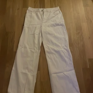 Vita jeans  - Säljer ett par vita jeans i mycket bra skick. De har en klassisk design med dragkedja och knapp framtill. Byxorna har en rak passform och är perfekta för både vardag och fest. De är tillverkade i ett bekvämt material som känns skönt mot huden.