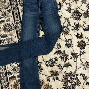 Blå jeans från G by Guess - Säljer ett par snygga blå jeans från Gina i storlek XS. De är utsvängda passform och är i bra skick. Jeansen har en dragkedja och knappar framtill samt slitsdetaljer vid bensluten. Perfekta för både vardag och fest! Aldrig använt 
