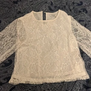 Vit spetsblus från NA-KD - Säljer en superfin vit spetsblus från NA-KD i storlek 34. Blusen har långa ärmar och är helt i spets vilket ger en romantisk look. Perfekt för både vardag och fest! Den är i mycket bra skick och redo för en ny ägare.