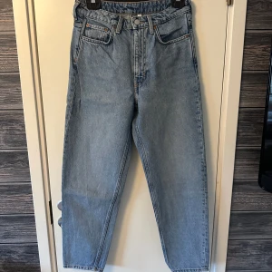 Blå jeans från Weekday - Säljer ett par klassiska blå jeans från Weekday. Dessa jeans är högmidjade mom jeans. De är tillverkade i slitstarkt denim och har traditionella fem fickor samt knappgylf.