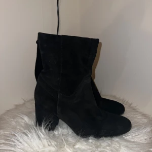 Svarta mockastövlar med klack - Säljer ett par snygga svarta stövlar i mocka med klack. De är i bra skick och perfekta för höst och vinter. Stövlarna har en stilren design och är bekväma att bära. Passar både till vardags och festliga tillfällen.