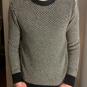 Svartvit mönstrad tröja från H&M Edition - Säljer en stilren svartvit mönstrad tröja från H&M Edition. Tröjan är i mycket bra skick och har en klassisk passform med långa ärmar. Perfekt för både höst och vinter. Den är gjord i ett mjukt material som håller dig varm och bekväm. Passar både till vardags och lite finare tillfällen.