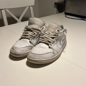 Vita Nike Air Jordans low - Säljer ett par vita Nike Air Jordans i bra skick. De har en klassisk design med snörning och är perfekta för vardagsbruk. Skorna har en snygg och stilren look, men det finns lite slitage på sulorna. Perfekta för dig som älskar sneakers med en ikonisk stil!