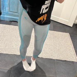 Ljusblå leggings med turkosa detaljer - Snygga ljusblå leggings med turkosa linjer som ger en sportig look. Perfekta för träning eller en aktiv vardag. De har en tight passform och är tillverkade i ett stretchigt material för bästa komfort. Jättefina sköna träningsbyxor! Knappt använda. I storlek s från gymshark!🥰
