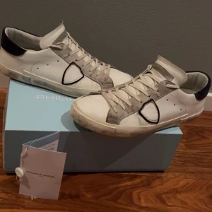 Vita sneakers från Philippe Model - Snygga vita sneakers från Philippe Model med mörkblå detaljer. Fint skick allt OG finns med. Skriv vid intresse, priset är inte hugget i sten