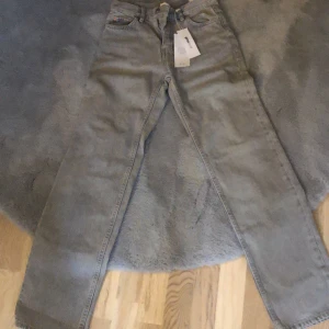 Grå jeansbyxor från Gina tricot - Snygga grå jeansbyxor från Gina tricot med klassisk design. De har en rak passform och är perfekta för en avslappnad stil. Byxorna har fem fickor och en knappgylf. Helt nya och inte blivit använda en gång.