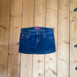 Jeanskjol från Miss Sixty - Snygg jeanskjol från Miss Sixty i mörkblå denim. Kjolen har klassisk femficksdesign med tydliga sömmar och en low waist modell. Perfekt för en avslappnad stil. Omsydd från jeans (noggrant) 