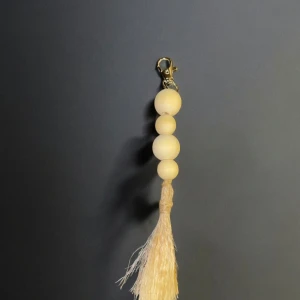 Nyckelring med träpärlor och tofs - Elegant nyckelring med fyra runda träpärlor i ljus färg och en dekorativ tofs. Perfekt som accessoar för att ge en naturlig touch till dina nycklar eller väska.