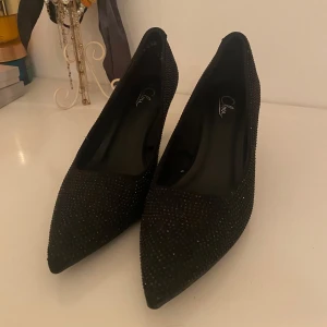 Svarta glittriga pumps från Clou - Snygga svarta pumps från Clou med glittrig yta och spetsig tå. Använda en gång, i princip nyköpa men passade inte mig tyvärr. 