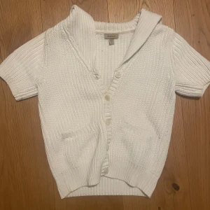 Vit stickad kofta från Gant - Säljer en vit stickad kofta från Gant med korta ärmar och knappar framtill. Den har en mysig krage och två fickor. Perfekt för lager på lager-stil. Passar till både vardag och mer avslappnade tillfällen. Skriv om intresserad innan köp nu🌸🌸