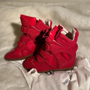 Röda sneakers från Isabel Marant - Snygga röda sneakers från Isabel Marant med en unik design. Skorna har en kombination av mocka och syntetmaterial samt en bekväm gummisula. De är helt nya men passar tyvärr inte mig.🥰