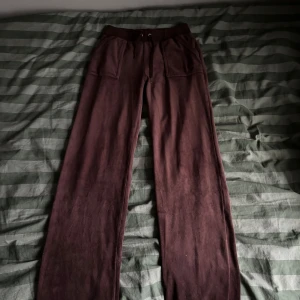 Bruna mjukisbyxor från Juicy Couture - Säljer ett par bruna mjukisbyxor från Juicy Couture i storlek XS. Byxorna har en bekväm passform med dragsko i midjan och praktiska fickor framtill. Perfekta för en avslappnad stil. Saknar en metall bit på snöret.