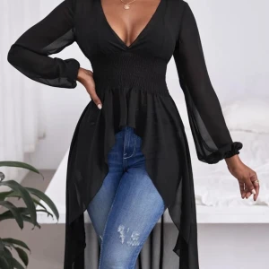 Svart lång blus med v-ringning - Snygg svart lång blus med v-ringning och långa ärmar. Blusen har en smockad midja och ett flödande, transparent tyg som ger en elegant look. Perfekt för att lyfta vilken outfit som helst.