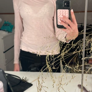 Ljusrosa långärmad topp - Säljer en ljusrosa långärmad topp i mjukt material. Perfekt för en stilren och bekväm look. Passar bra till både jeans och kjol.