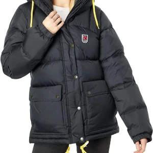 Svart dunjacka från Fjällräven - Säljer en svart dunjacka från Fjällräven med gula snören och en broderad logga på bröstet. Jackan har en pufferdesign med långa ärmar och praktiska fickor framtill. Perfekt för kyliga dagar! Den är i ett väldigt fint skick!