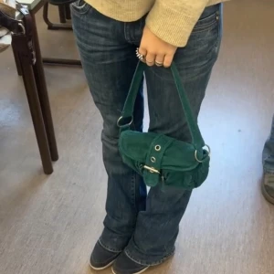 Grön axelväska i manchester - Snygg grön axelväska i manchester. Väskan har en praktisk design med spänne framtill. Perfekt för att ge din outfit en cool touch.💜