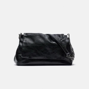 Svart axelväska med kedjedetaljer - Snygg svart axelväska i skinn med coola kedjedetaljer. Väskan har en stilren design med en bred axelrem och en praktisk storlek för alla dina nödvändigheter. Använd men inga defekter