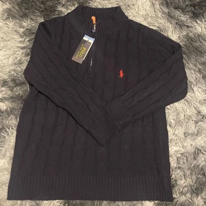 MÖRKBLÅ stickad tröja från Polo Ralph Lauren - Snygg MÖRKBLÅ stickad tröja från Polo Ralph Lauren med dragkedja vid halsen och röd broderad logga på bröstet.  EJ ORIGINAL 