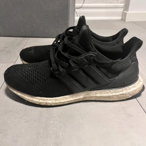 Svarta Adidas Ultraboost - Säljer ett par svarta Adidas Ultraboost sneakers. Skorna har en stickad ovandel och en bekväm Boost-sula för extra dämpning. Perfekta för både träning och vardag.