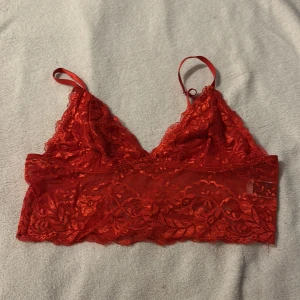 Röd spets bralette/linne från Shein - Säljer en snygg röd spets bralette/linne från Shein. Den har justerbara axelband och ett vackert spetsmönster. Perfekt för att lägga till en touch av färg och stil till din outfit.