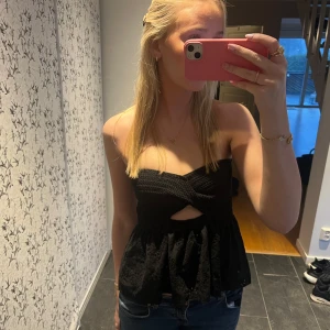 Svart axelbandslös topp - Snygg svart axelbandslös topp med twistdetalj framtill och en liten öppning under bysten, sååå snygg och endast använd nån gång🫶🏼🫶🏼💗