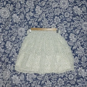 Blommig kortkjol - Söt kortkjol med blommigt mönster i ljusa färger. Kjolen har en volangdetalj och elastisk midja för bekväm passform. Perfekt för varma dagar.