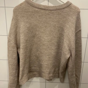 Beige stickad tröja från 157 - Säljer en mysig beige stickad tröja från 157. Tröjan har en enkel design med långa ärmar och ribbstickade kanter. Perfekt för kyliga dagar.